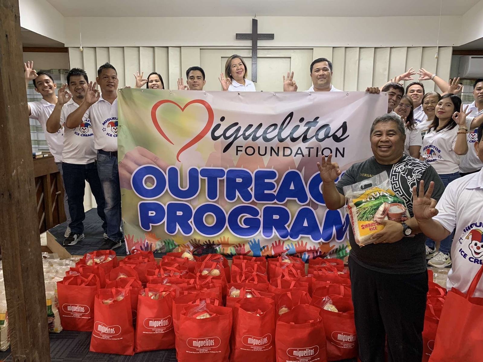 Volunteers with an outreach program banner and gift bags
