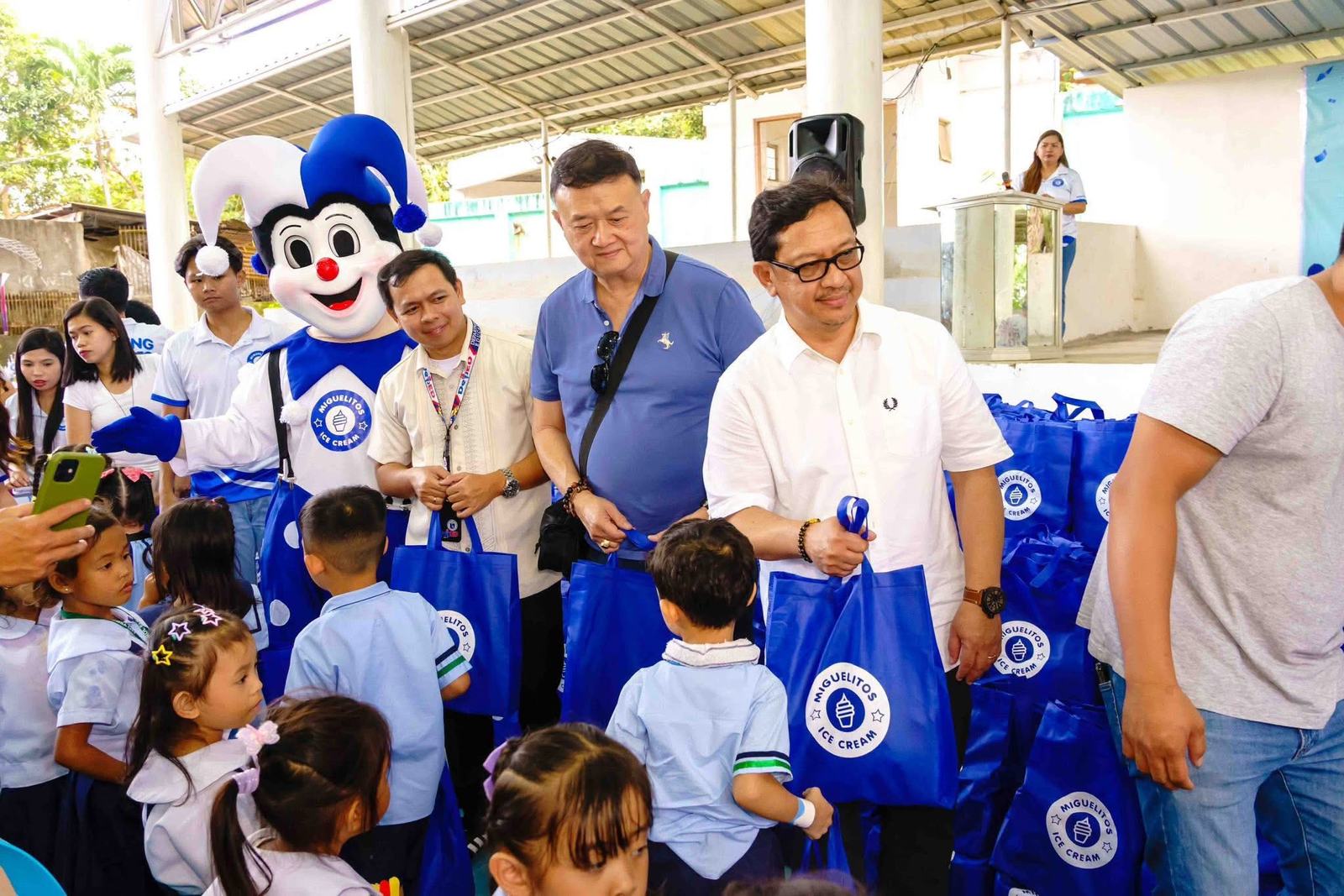 Volunteers with the mascot and children holding gift bags