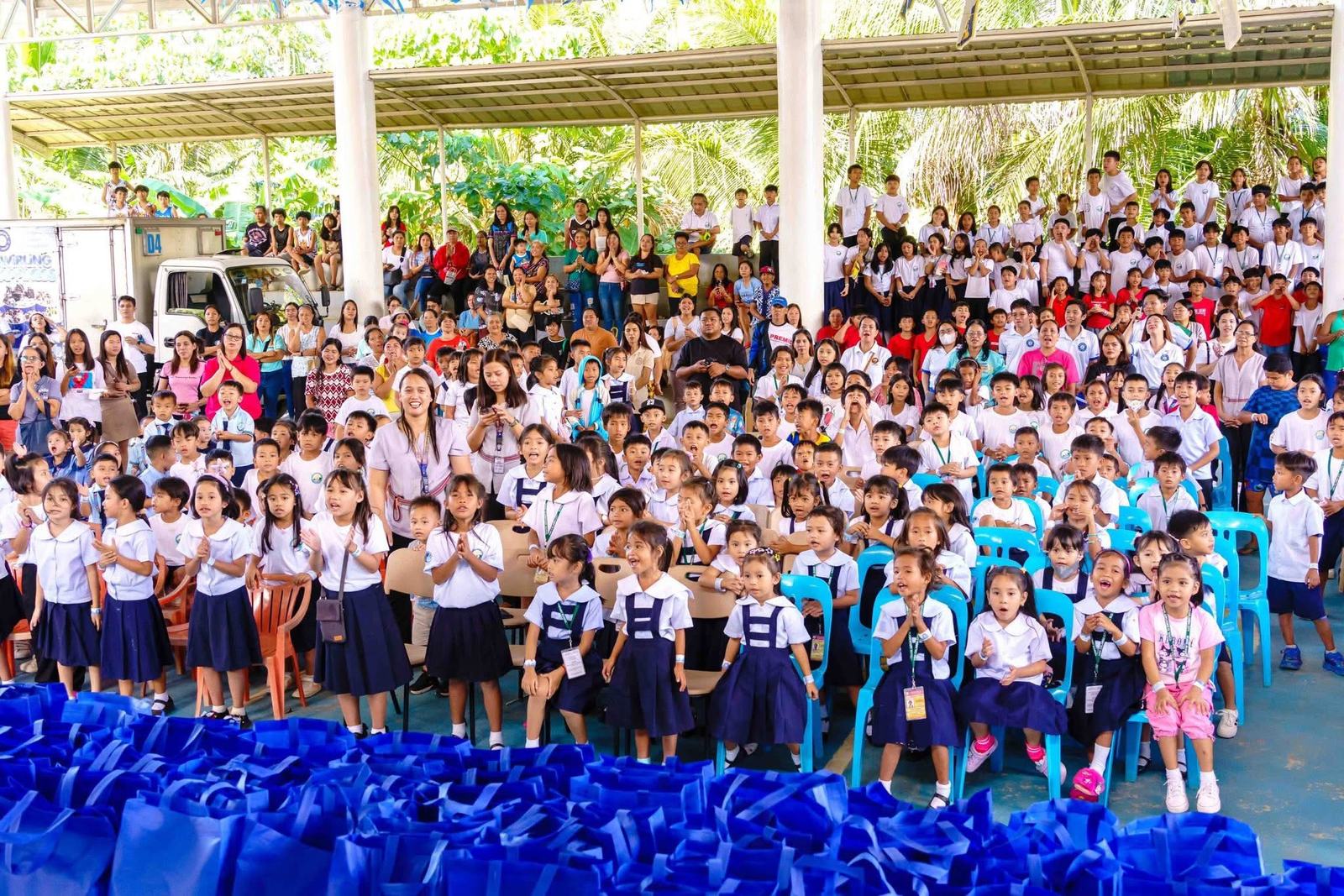 A large gathering of students with blue gift bags